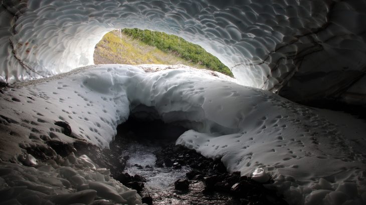 Ice cave with plants outside in spring