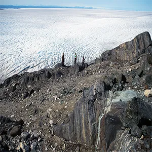 Claire Nichols and colleagues stand on the outcrop of a banded iron formation containing the oldest records of Earth’s magnetic field. The Greenland ice sheet is in the background. Credit: Claire Nichols/MIT